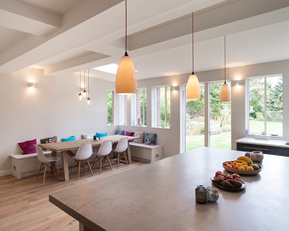 Photo of a large contemporary l-shaped kitchen/diner in London with a built-in sink, flat-panel cabinets, grey cabinets, concrete worktops, integrated appliances, medium hardwood flooring and a breakfast bar.