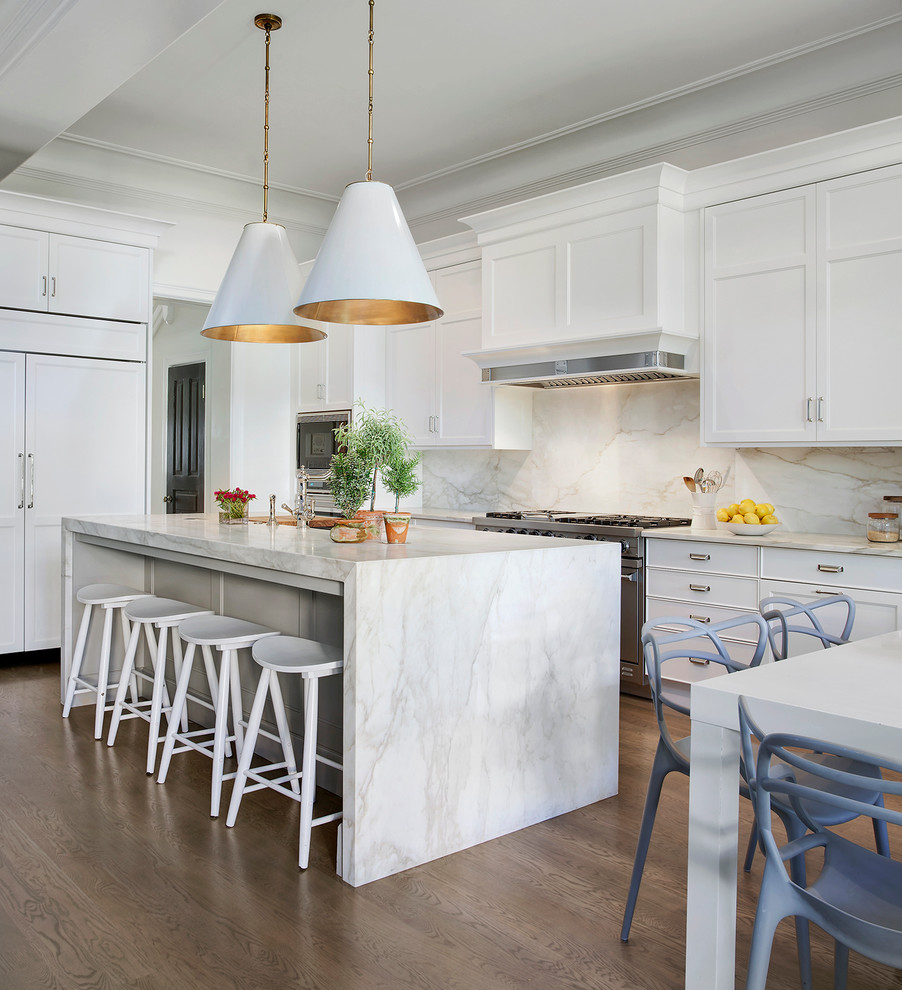 Photo of a large transitional l-shaped eat-in kitchen in Chicago with marble benchtops, white splashback, stone slab splashback, recessed-panel cabinets, white cabinets, panelled appliances, medium hardwood floors, with island and an undermount sink.