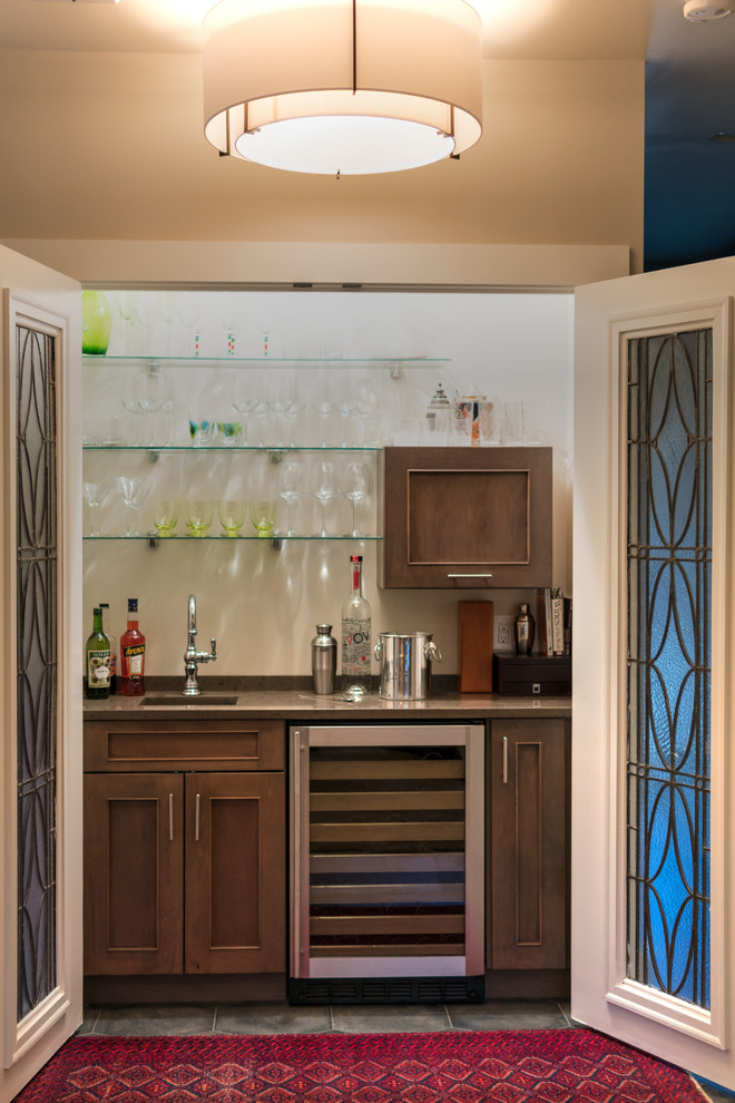 Photo of a large arts and crafts l-shaped home bar in Boston with an integrated sink, recessed-panel cabinets, grey cabinets, granite benchtops, blue splashback, ceramic splashback, light hardwood floors and brown floor.