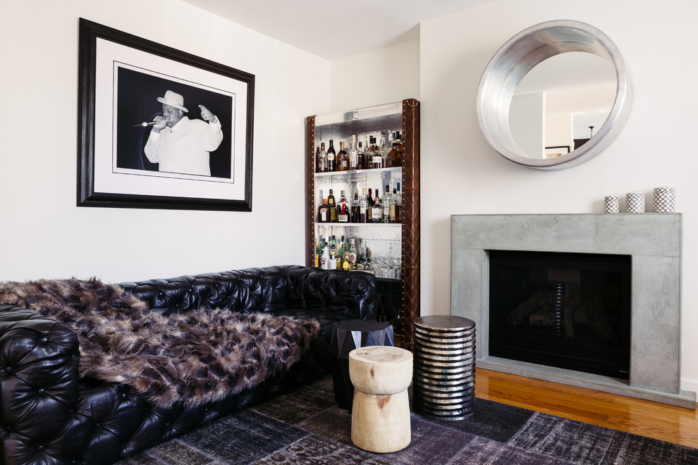 Photo of an eclectic enclosed living room in Melbourne with white walls, medium hardwood floors, a standard fireplace, a concrete fireplace surround and no tv.