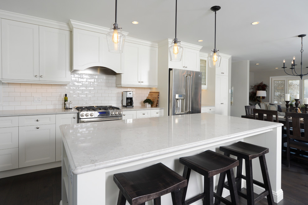 Inspiration for a large transitional l-shaped eat-in kitchen in Toronto with a double-bowl sink, shaker cabinets, white cabinets, marble benchtops, yellow splashback, subway tile splashback, stainless steel appliances, dark hardwood floors and with island.