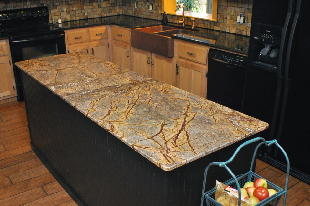 Example of a mountain style kitchen design with a farmhouse sink, light wood cabinets, marble countertops, multicolored backsplash, black appliances and an island