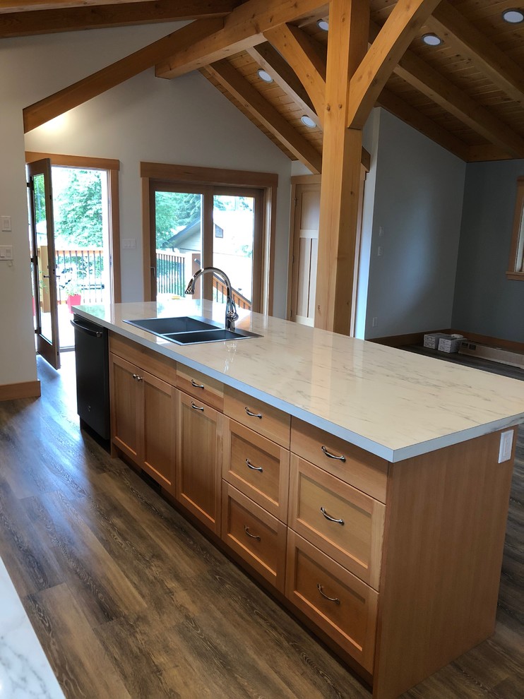 Photo of a small arts and crafts l-shaped eat-in kitchen in Vancouver with a drop-in sink, shaker cabinets, laminate benchtops, black appliances, laminate floors, with island, grey floor and white benchtop.