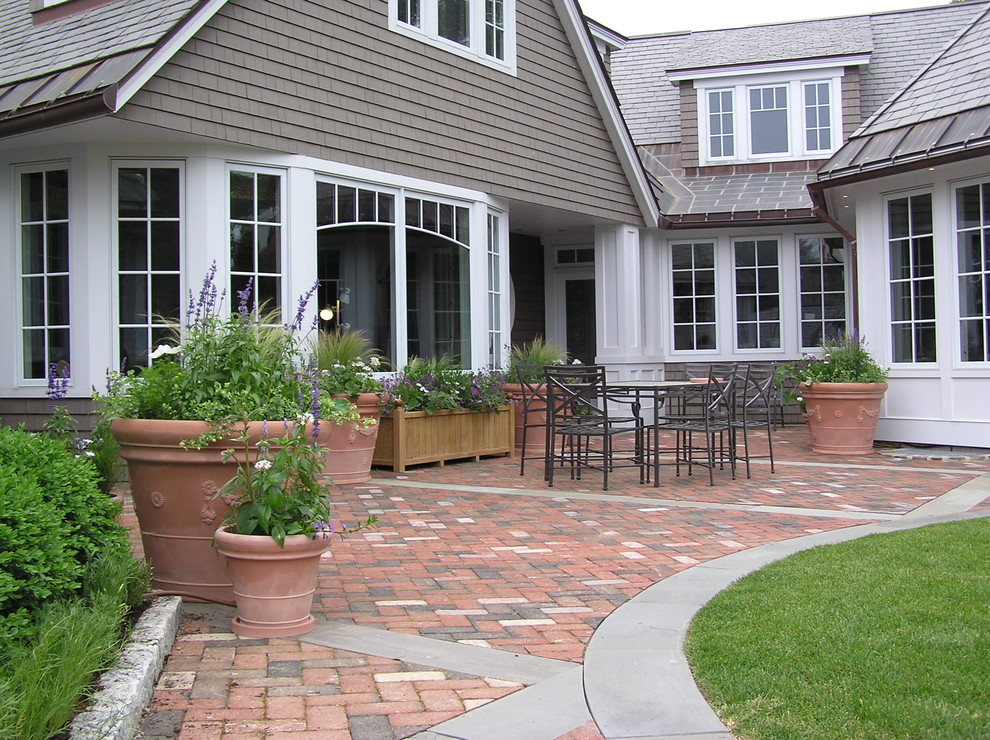 This is an example of a traditional patio in Manchester with brick pavers and no cover.