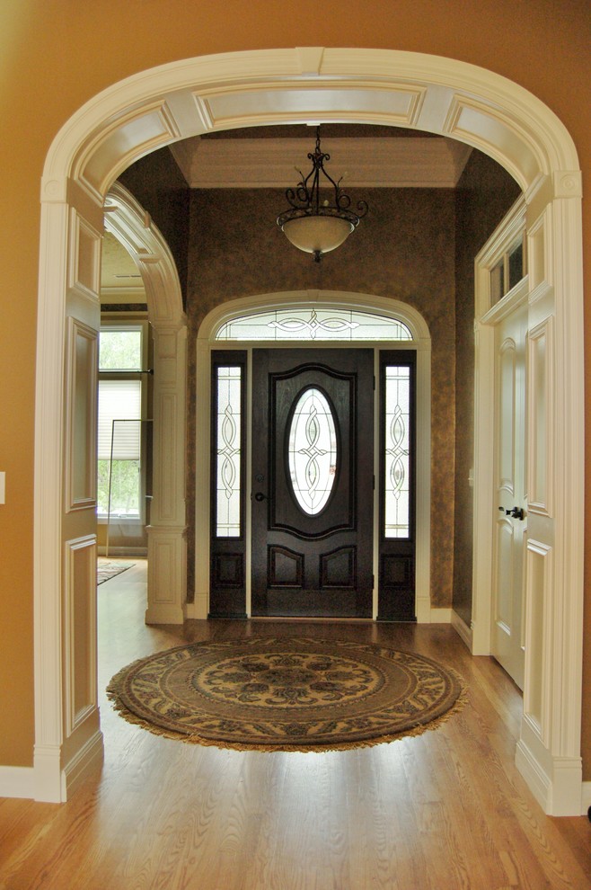Photo of a mid-sized traditional foyer in Other with metallic walls, light hardwood floors, a single front door and a dark wood front door.