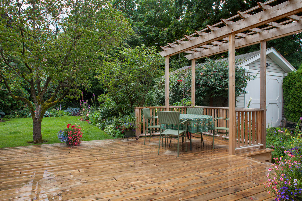 Mid-sized traditional backyard deck in Portland with a pergola.