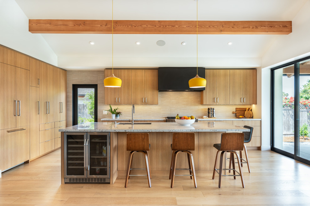 Open concept kitchen - 1960s medium tone wood floor and vaulted ceiling open concept kitchen idea in San Diego with a drop-in sink, flat-panel cabinets, medium tone wood cabinets, terrazzo countertops, gray backsplash, ceramic backsplash, paneled appliances, an island and white countertops