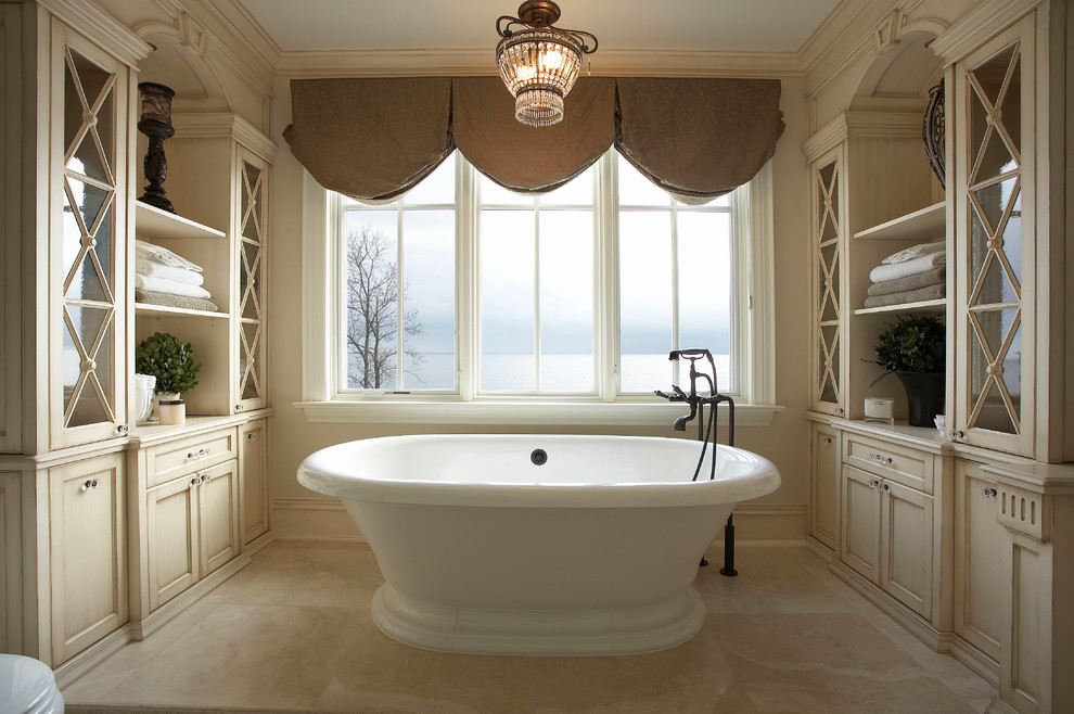 Design ideas for a large traditional master bathroom in Toronto with recessed-panel cabinets, distressed cabinets, a freestanding tub and beige tile.