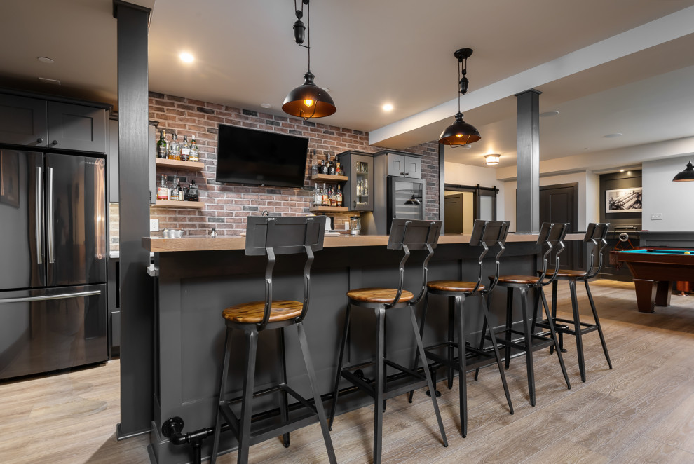 Inspiration for a large industrial galley seated home bar in Philadelphia with an undermount sink, shaker cabinets, grey cabinets, wood benchtops, multi-coloured splashback, brick splashback, vinyl floors, beige floor and beige benchtop.