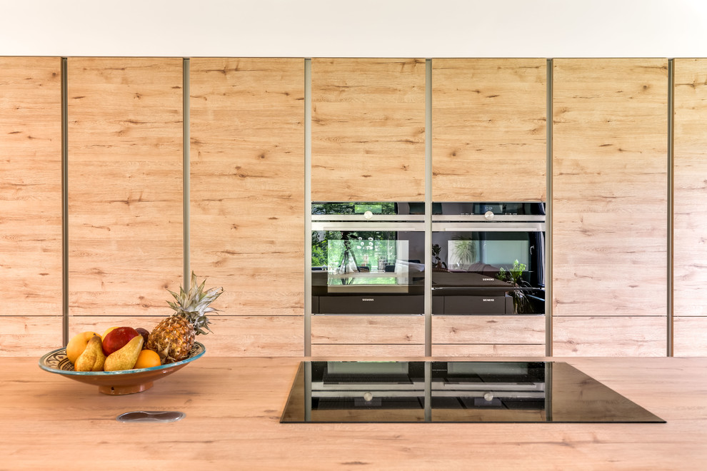 This is an example of a contemporary l-shaped open plan kitchen in Strasbourg with a double-bowl sink, light wood cabinets, laminate benchtops, mosaic tile splashback, stainless steel appliances, concrete floors, with island and beige floor.