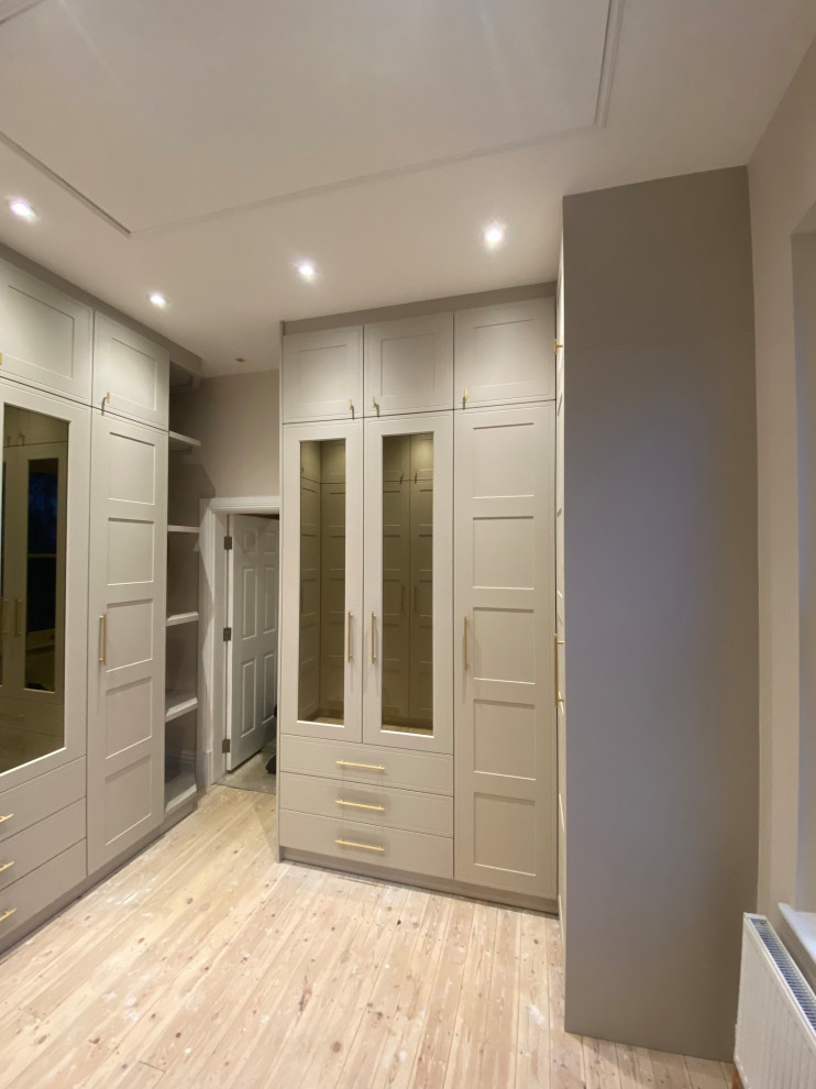 Design ideas for a large victorian built-in wardrobe in Other with shaker cabinets, beige cabinets, medium hardwood flooring, yellow floors and feature lighting.
