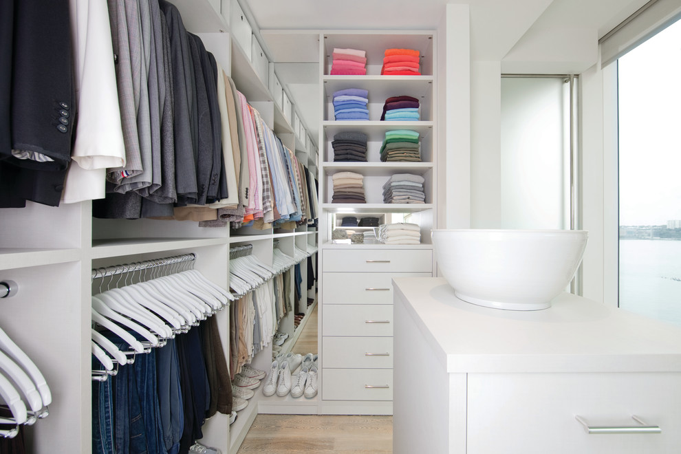 Inspiration for a large modern gender-neutral dressing room in Jacksonville with flat-panel cabinets, white cabinets, light hardwood floors and beige floor.