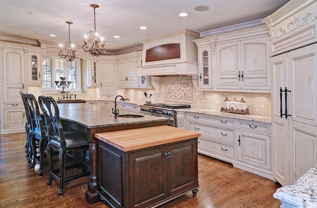 Eat-in kitchen - large transitional u-shaped medium tone wood floor eat-in kitchen idea in Chicago with a farmhouse sink, raised-panel cabinets, white cabinets, granite countertops, white backsplash, stone tile backsplash, colored appliances and an island