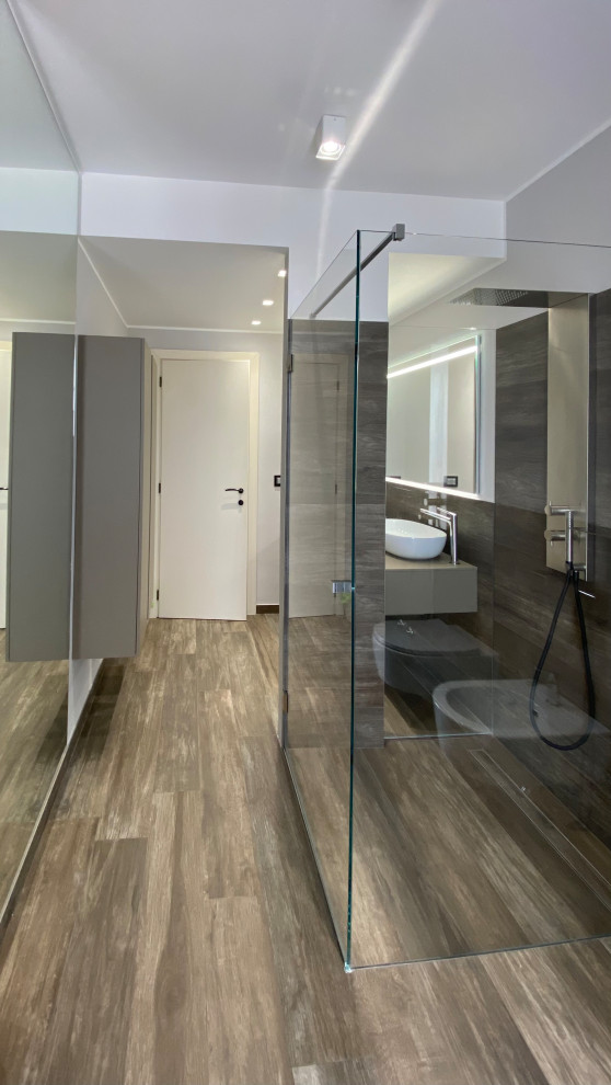 This is an example of a mid-sized contemporary master bathroom with flat-panel cabinets, beige cabinets, a curbless shower, porcelain tile, grey walls, porcelain floors, a vessel sink, wood benchtops, a hinged shower door, beige benchtops, a floating vanity and recessed.