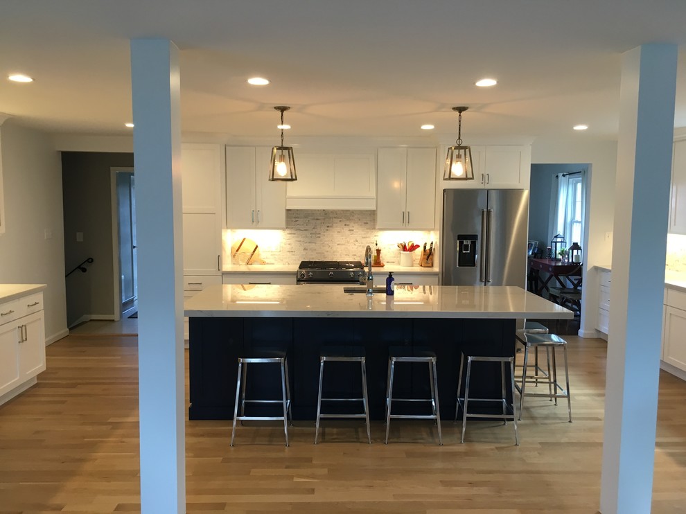 Example of a mid-sized transitional u-shaped brown floor open concept kitchen design in DC Metro with an undermount sink, shaker cabinets, white cabinets, gray backsplash, stainless steel appliances, an island and white countertops