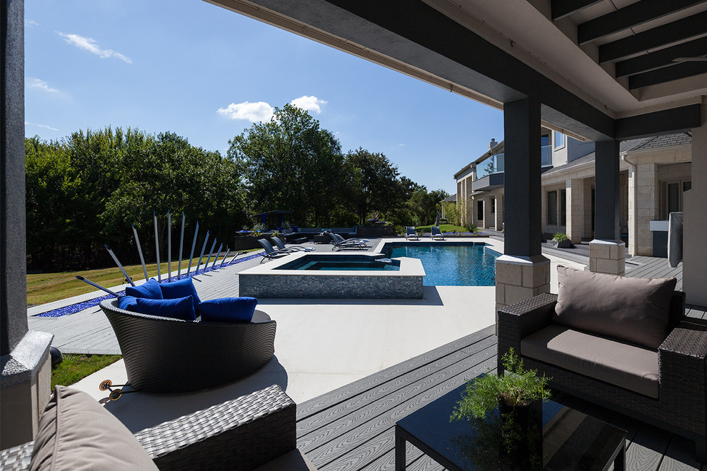 This is an example of a large contemporary backyard patio in Dallas with an outdoor kitchen, concrete pavers and a roof extension.