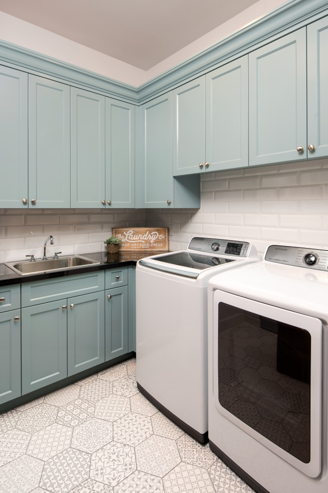 Mid-sized country l-shaped dedicated laundry room in Phoenix with a drop-in sink, recessed-panel cabinets, blue cabinets, quartz benchtops, grey walls, ceramic floors, a side-by-side washer and dryer, white floor and black benchtop.