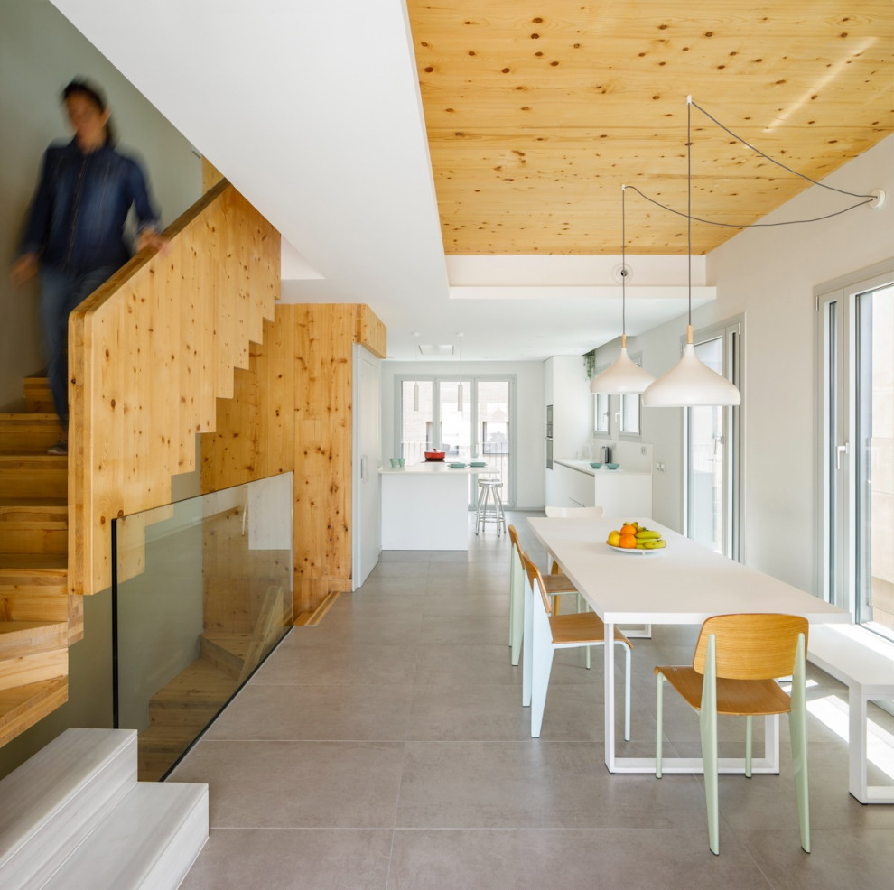 Esempio di una sala da pranzo aperta verso il soggiorno scandinava di medie dimensioni con pareti bianche, pavimento in gres porcellanato, pavimento grigio, soffitto in legno e pareti in legno
