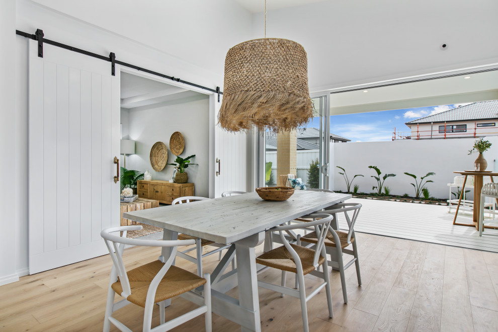 Design ideas for a mid-sized beach style open plan dining in Melbourne with white walls, a standard fireplace and a stone fireplace surround.