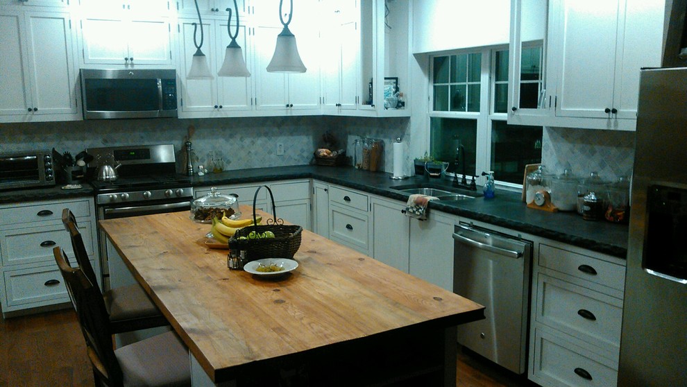 Example of a mid-sized transitional u-shaped dark wood floor and brown floor kitchen design with an undermount sink, recessed-panel cabinets, white cabinets, concrete countertops, multicolored backsplash, ceramic backsplash, stainless steel appliances and black countertops