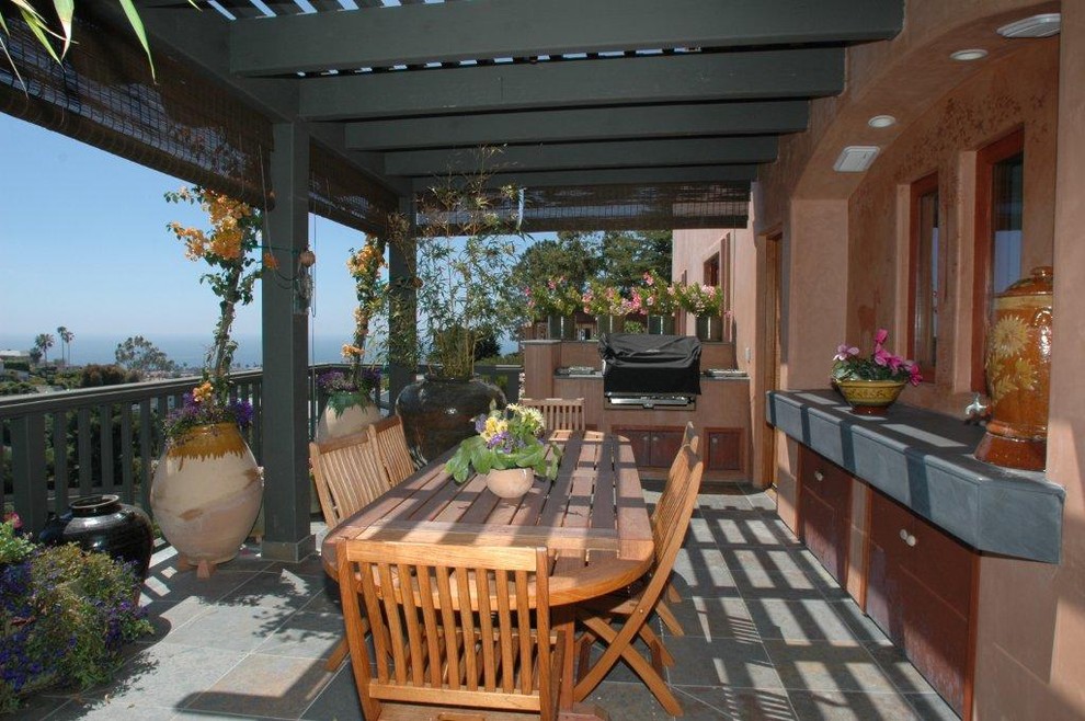 This is an example of a large asian backyard verandah in San Diego with an outdoor kitchen, tile and a pergola.