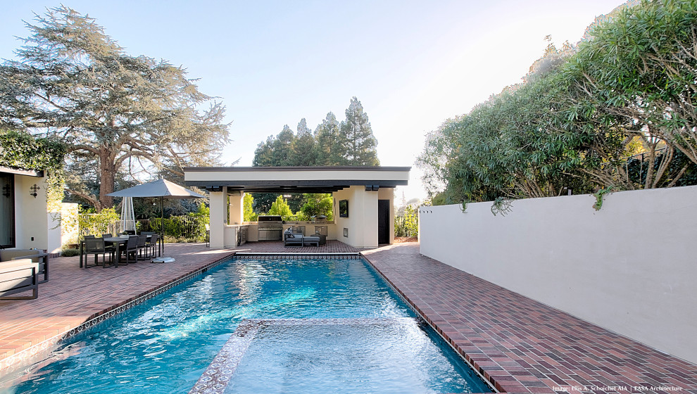 Small eclectic back swimming pool in San Francisco with brick paving.
