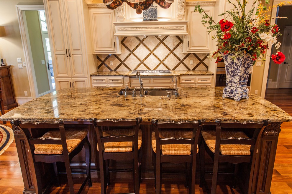 Eat-in kitchen - huge transitional u-shaped medium tone wood floor eat-in kitchen idea with an undermount sink, raised-panel cabinets, white cabinets, granite countertops, metallic backsplash, stone tile backsplash, stainless steel appliances and an island