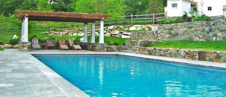 This is an example of a large modern backyard custom-shaped pool in New York with a hot tub and stamped concrete.