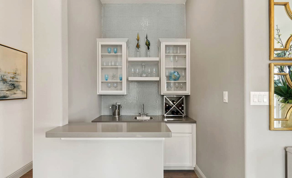 Contemporary single-wall wet bar in Dallas with a drop-in sink, recessed-panel cabinets, white cabinets, laminate floors, brown floor and grey benchtop.
