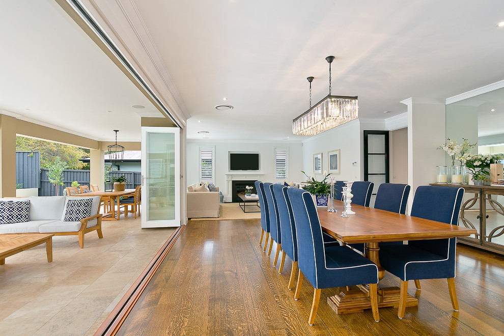 Photo of a large transitional open plan dining in Sydney with white walls, medium hardwood floors, a standard fireplace and a wood fireplace surround.