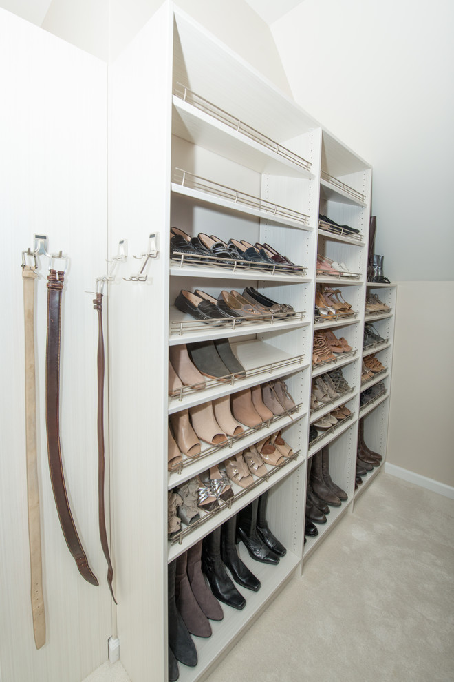 This is an example of a large modern gender-neutral walk-in wardrobe in Nashville with white cabinets, carpet and white floor.