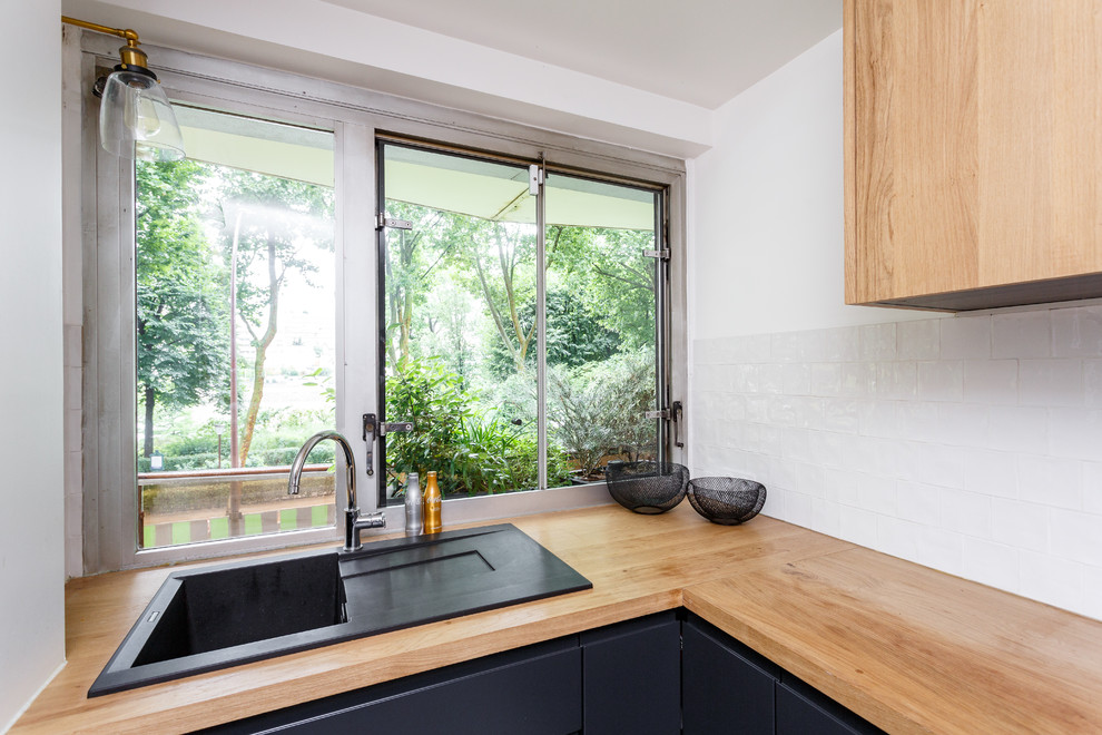 Small scandinavian l-shaped separate kitchen in Paris with a drop-in sink, flat-panel cabinets, black cabinets, wood benchtops, white splashback, ceramic splashback, stainless steel appliances, terrazzo floors, no island, multi-coloured floor and brown benchtop.
