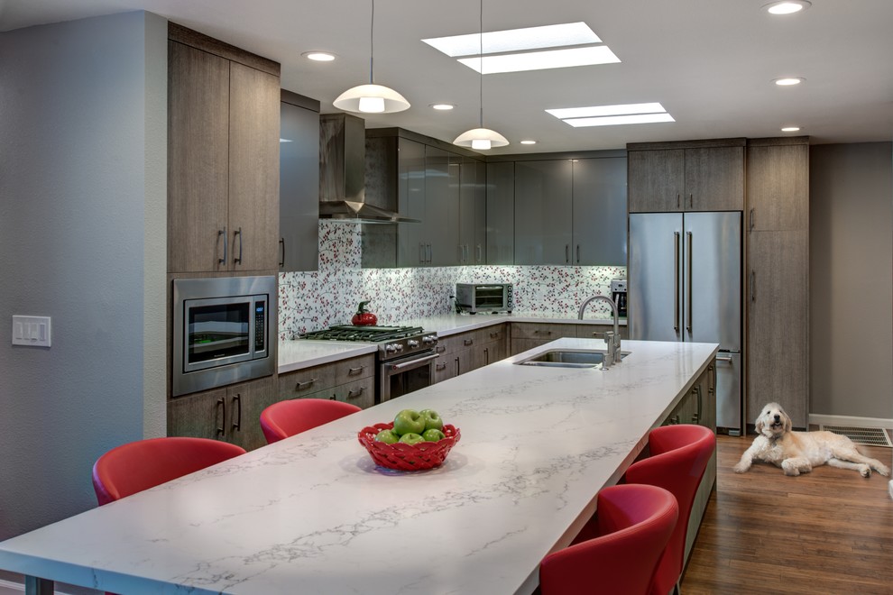 This is an example of a mid-sized contemporary l-shaped eat-in kitchen in San Francisco with an undermount sink, flat-panel cabinets, grey cabinets, quartz benchtops, red splashback, porcelain splashback, stainless steel appliances, medium hardwood floors and with island.