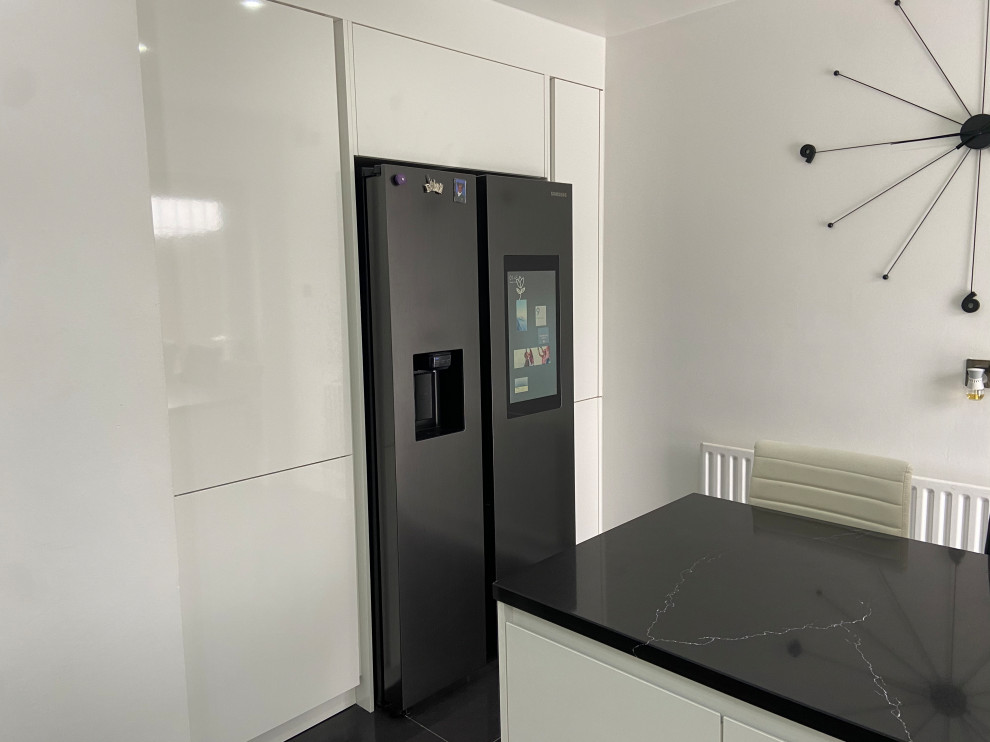 Moderne Wohnküche mit Quarzit-Arbeitsplatte, Küchenrückwand in Schwarz, Rückwand aus Quarzwerkstein, schwarzen Elektrogeräten und schwarzer Arbeitsplatte in London