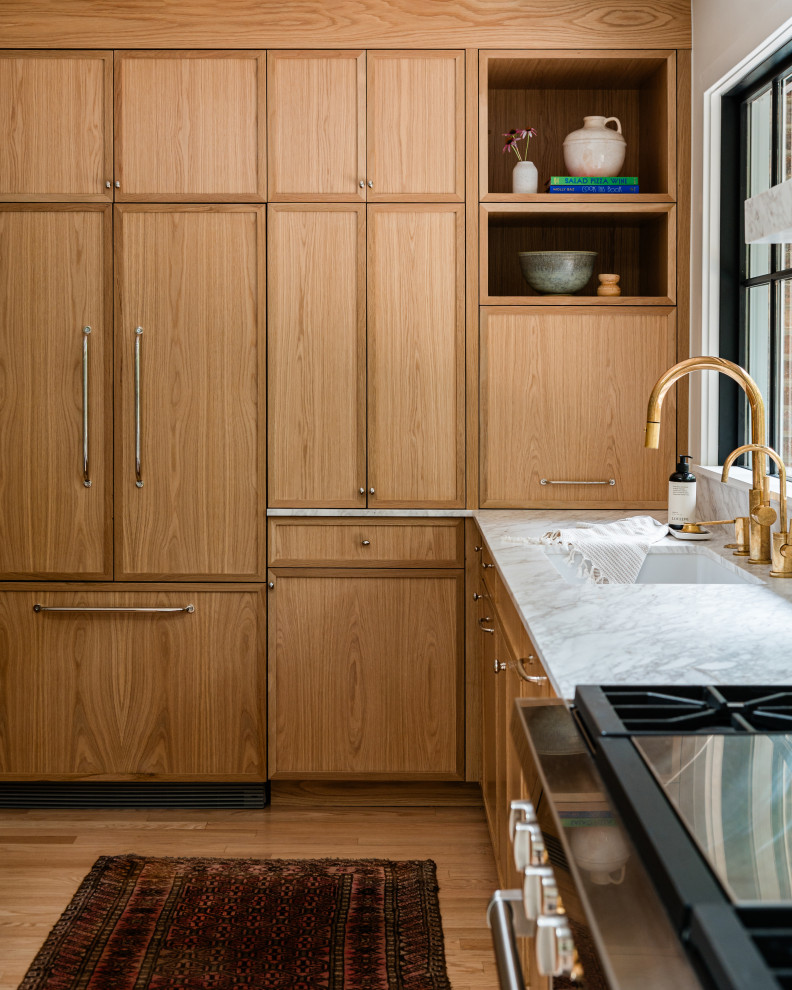 Mid-sized transitional l-shaped light wood floor eat-in kitchen photo in Chicago with an undermount sink, shaker cabinets, light wood cabinets, marble countertops, white backsplash, marble backsplash, paneled appliances, an island and white countertops