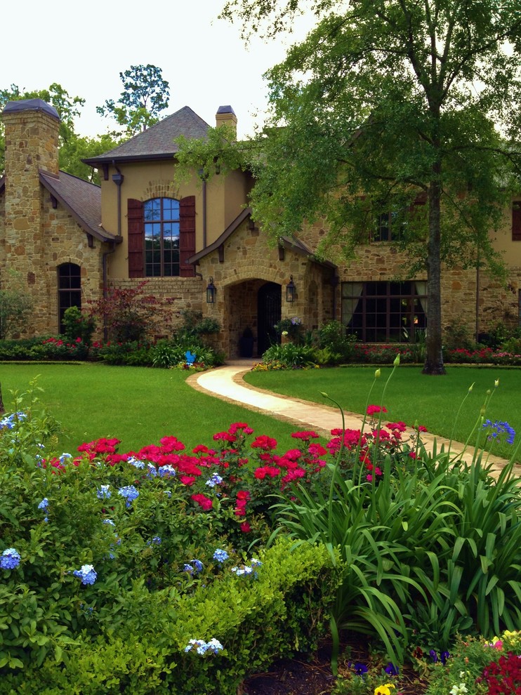 Large mediterranean front yard full sun formal garden in Houston with a garden path and natural stone pavers for summer.