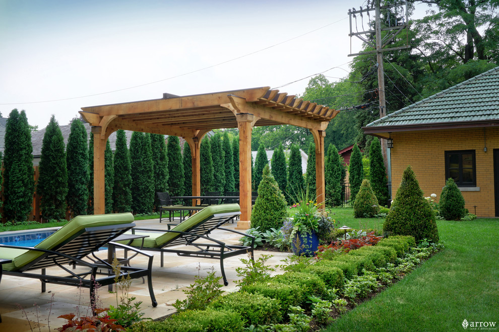 This is an example of a mid-sized traditional backyard patio with a container garden, natural stone pavers and a pergola.