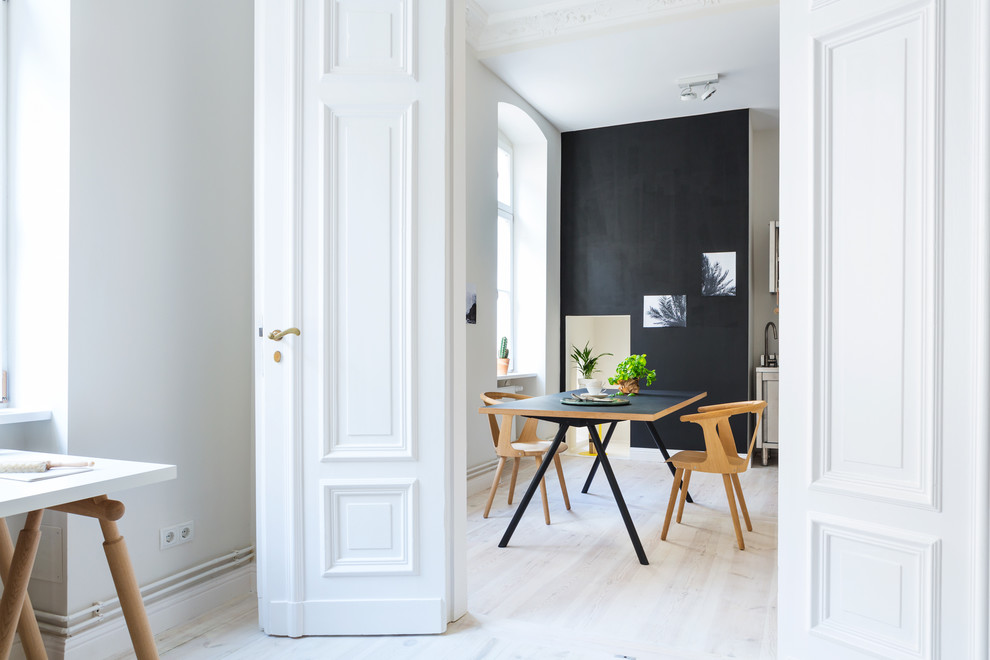 Mid-sized contemporary separate dining room in Berlin with black walls and light hardwood floors.