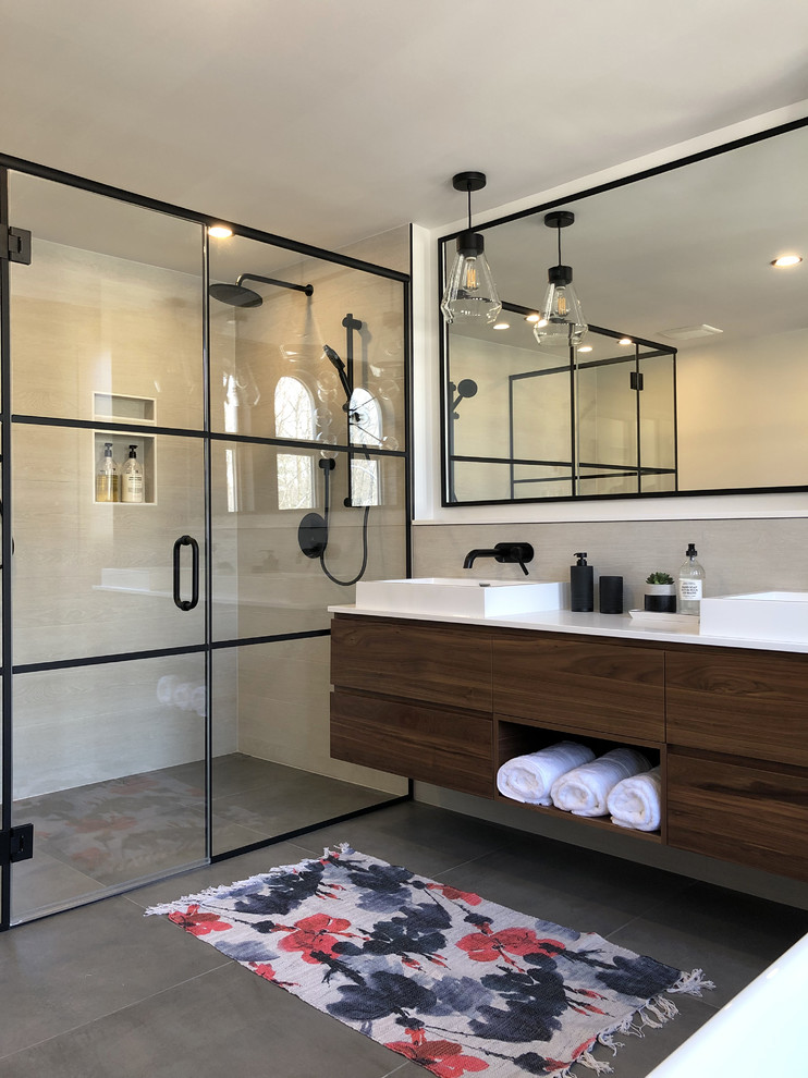 Photo of a mid-sized contemporary master bathroom in Montreal with flat-panel cabinets, a two-piece toilet, beige tile, porcelain tile, porcelain floors, solid surface benchtops, grey floor, a hinged shower door, white benchtops, dark wood cabinets, a curbless shower, white walls and a vessel sink.
