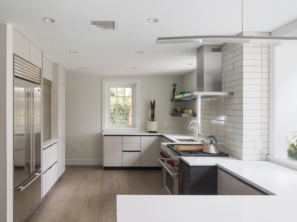 Contemporary kitchen in Philadelphia with an undermount sink, flat-panel cabinets, beige cabinets, white splashback, stainless steel appliances, medium hardwood floors and a peninsula.