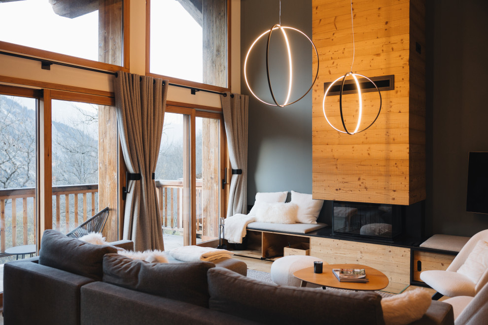 Idée de décoration pour un salon chalet avec un mur gris, parquet clair, une cheminée standard, un manteau de cheminée en bois, un téléviseur fixé au mur et un sol beige.