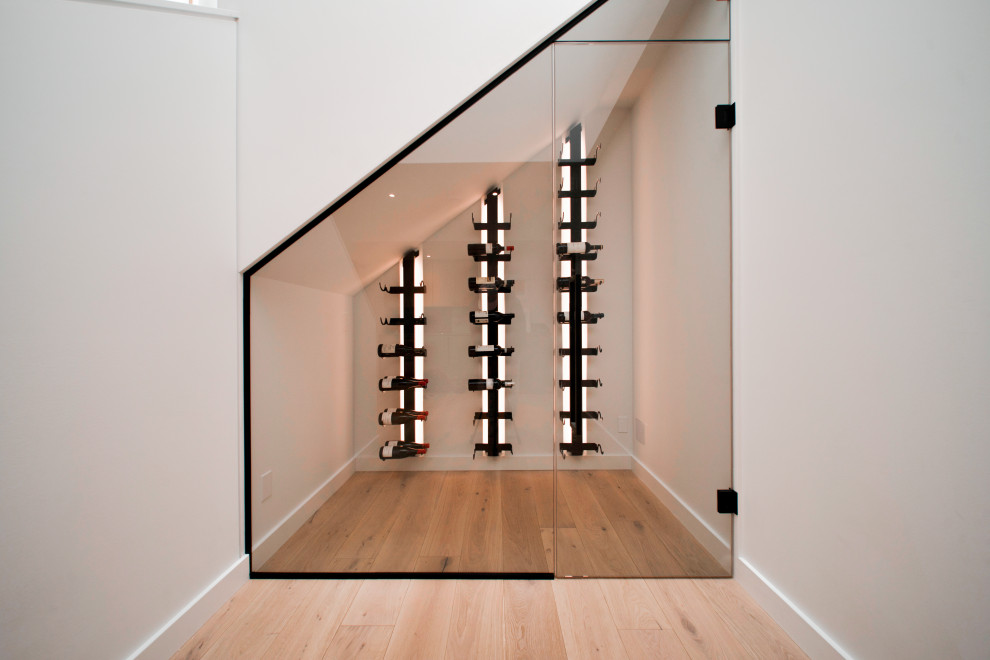 Wine cellar - small modern light wood floor and beige floor wine cellar idea in Calgary with storage racks