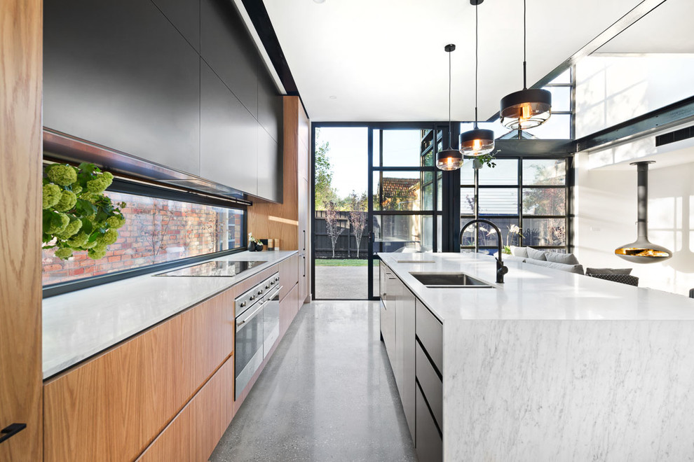 Inspiration for a mid-sized contemporary galley eat-in kitchen in Melbourne with an undermount sink, raised-panel cabinets, medium wood cabinets, marble benchtops, glass sheet splashback, stainless steel appliances, concrete floors and with island.