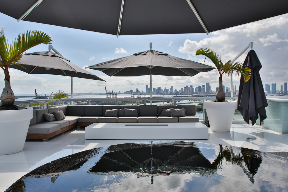 Mid-sized contemporary rooftop rectangular infinity pool in Miami with concrete slab and a hot tub.