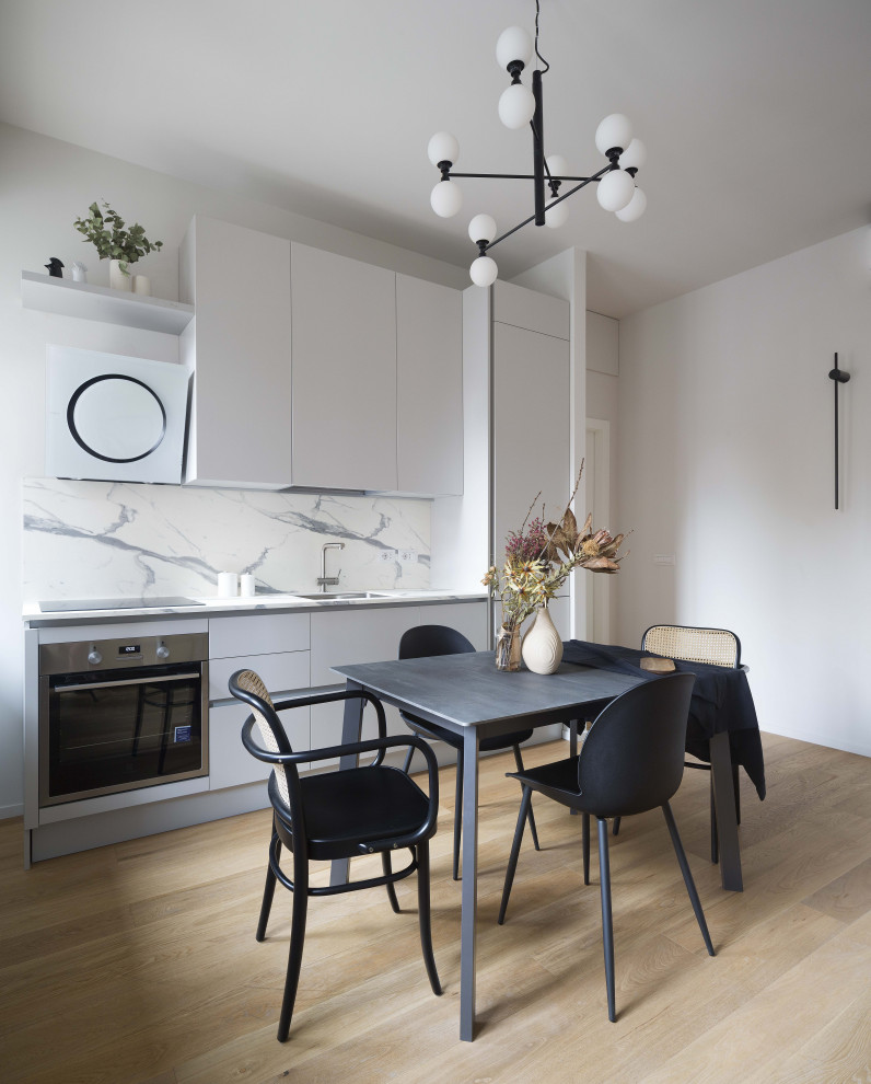 Design ideas for a mid-sized contemporary single-wall eat-in kitchen in Milan with an undermount sink, flat-panel cabinets, beige cabinets, white splashback, light hardwood floors, no island, beige floor and white benchtop.