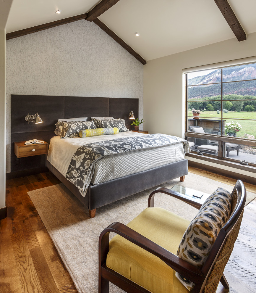 Ejemplo de dormitorio rural con paredes blancas, suelo de madera en tonos medios y suelo marrón