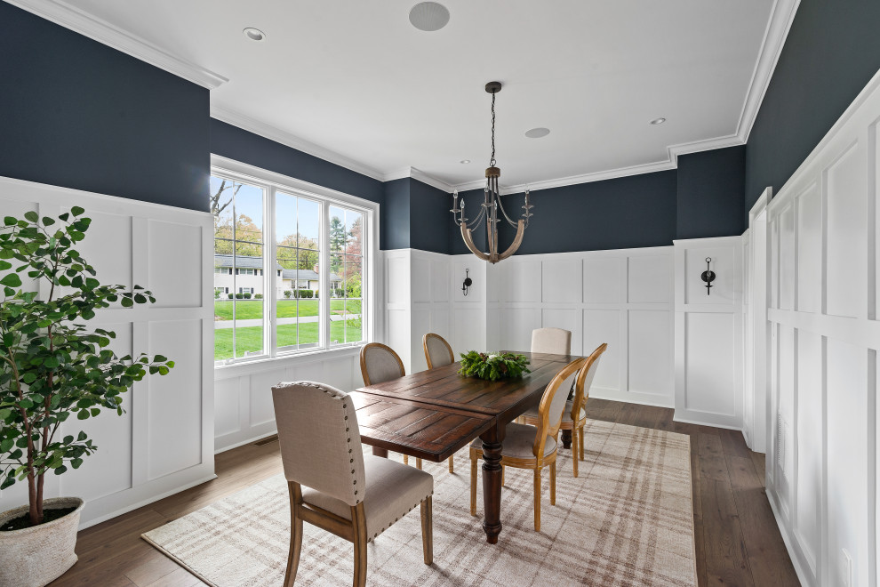 На фото: отдельная столовая в стиле модернизм с синими стенами, коричневым полом и панелями на части стены