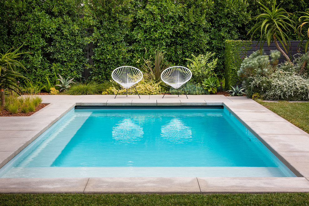 Midcentury backyard rectangular pool in Orange County with concrete slab.