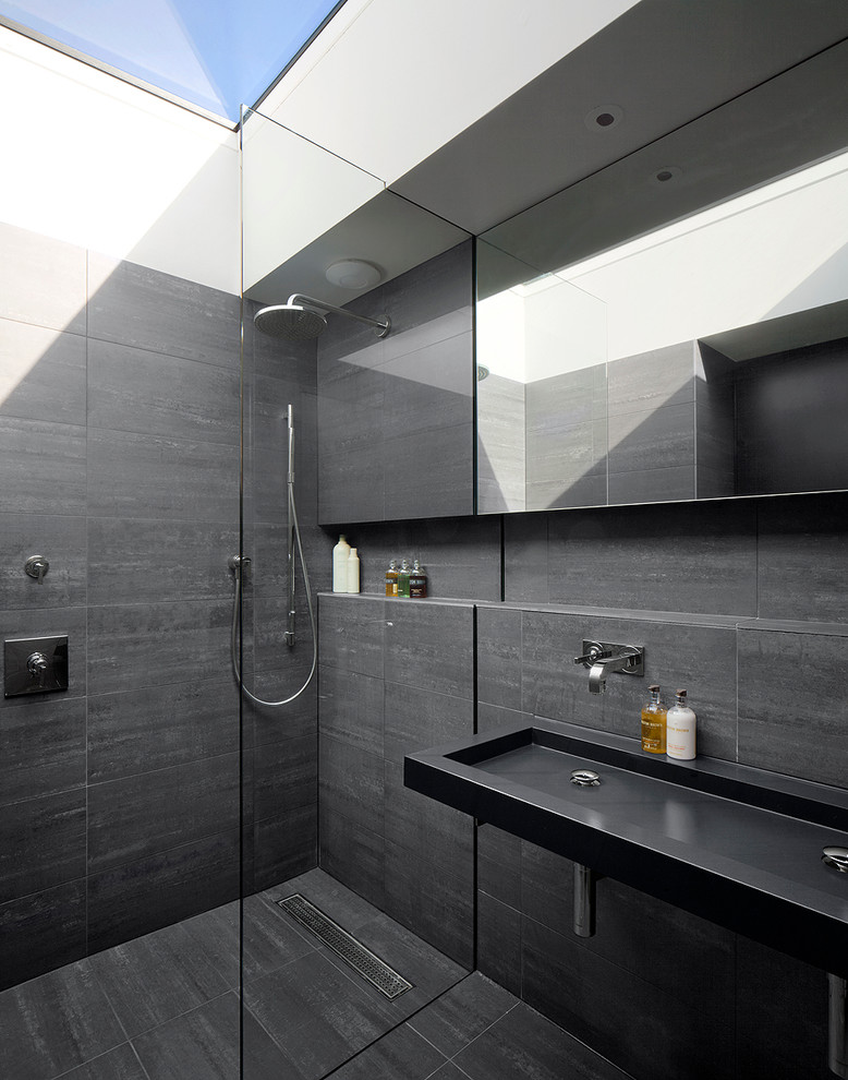 Contemporary 3/4 bathroom in London with a trough sink, a curbless shower, gray tile and grey walls.