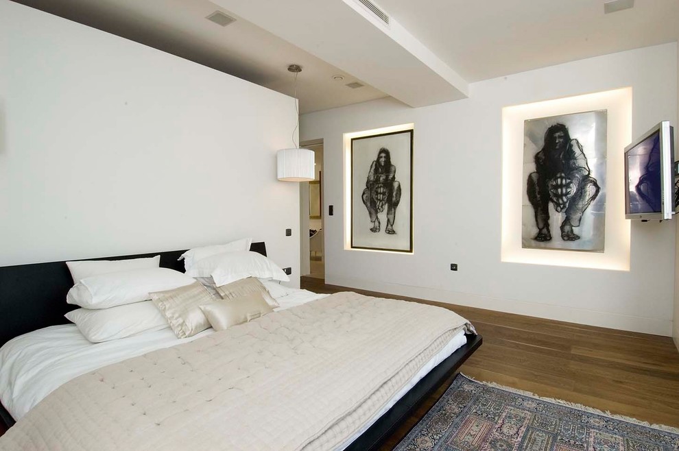 Design ideas for a mid-sized modern bedroom in London with white walls, medium hardwood floors and brown floor.